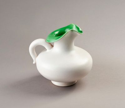un petit vase blanc surmonté d'une feuille verte