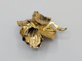 an image of a gold plated flower brooch on a white surface