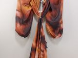 an orange and black tie dyed scarf hanging on a white wall