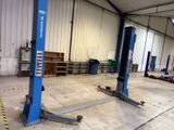 two large blue lifts in a garage with other equipment