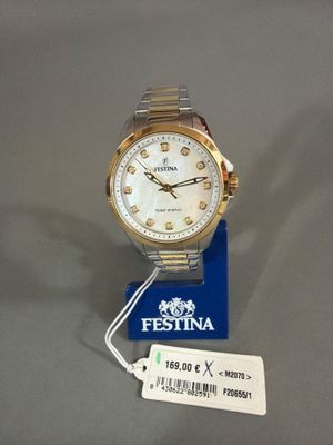 une photo d'une montre dorée et blanche sur laquelle est accrochée une étiquette