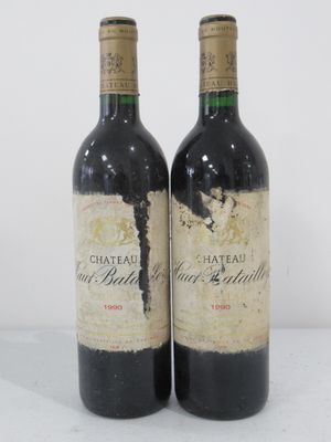 two bottles of red wine sitting on top of a white table