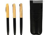 un lot composé de trois stylos noirs et dorés et d'un étui