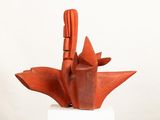 a red sculpture on a white pedestal with a white background