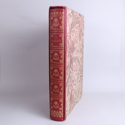 an old book with a red cover sitting on top of a white table