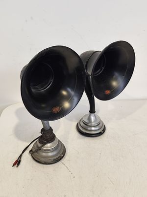 une paire d'enceintes noires posées sur une table blanche, sur fond blanc