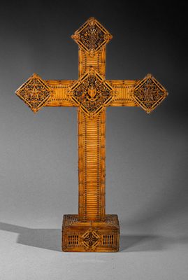 an ornate wooden cross on a stand with a shadow
