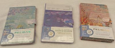 four books are lined up on a table with a white table cloth