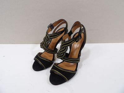 une paire de talons hauts noirs et jaunes posés sur une surface blanche