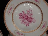 three plates with pink flowers on them sitting on a table