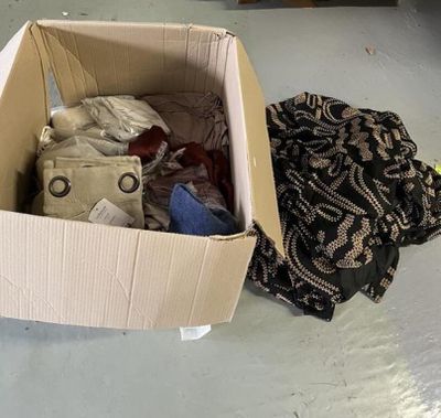 une boîte en carton remplie de vêtements posée par terre
