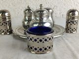 a silver plate with a blue glass and silver salt and pepper shakers on it