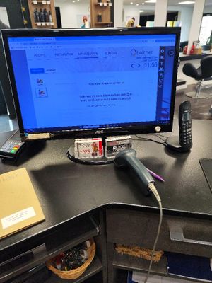 a desk with a laptop, phone, and a monitor on it