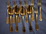 a lot of forks and spoons on a blue cloth