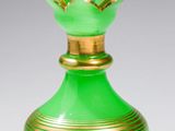 vase en verre vert orné d'une bordure dorée, posé sur une surface blanche