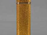 a gold lighter sitting on top of a table next to a gray background