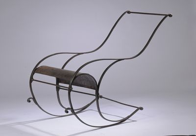 un fauteuil à bascule en fer avec une assise en bois, posé sur une surface blanche
