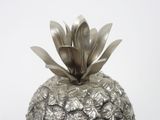 a silver metal pineapple with a flower on top