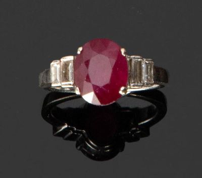 une bague ovale sertie d'un rubis et de diamants en taille baguette sur un fond noir