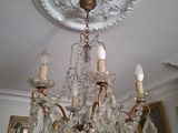 un lustre dans une pièce où sont accrochés des tableaux aux murs