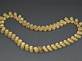 a gold necklace and bracelet set with a flower design