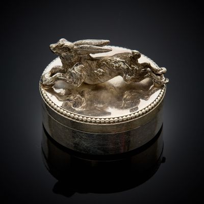 une boîte ancienne en argent, ornée d'un chien sur un fond noir