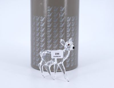 a glass deer figurine that is standing next to a can