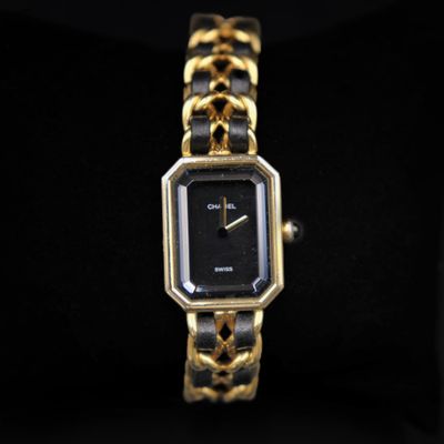 a close up of a gold and black watch on a black surface