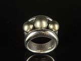 a close up of a silver ring with pearls on a black surface