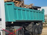 un camion-benne vert garé à côté d'un immeuble