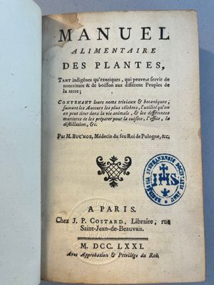 un livre ouvert posé sur une table, sur lequel se trouve un tampon