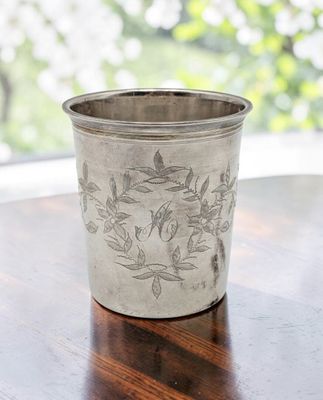 une coupe en argent posée sur une table en bois devant une fenêtre