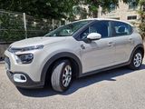 La voiture est garée sur le parking, à côté d'une clôture.