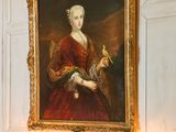 un tableau représentant une femme en robe rouge et une horloge posée sur une table