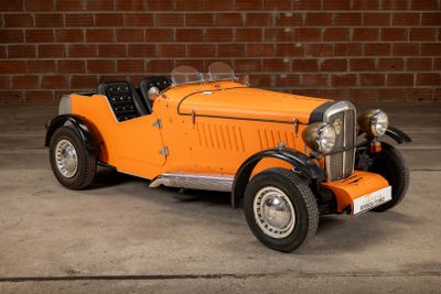 an orange model of a car parked in front of a brick wall