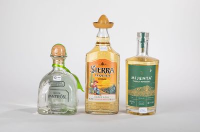 Trois bouteilles d'alcools de différentes sortes sont alignées sur une surface blanche
