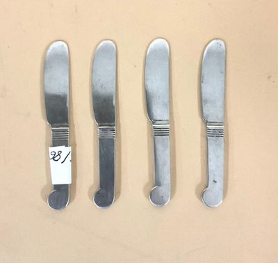 trois couteaux et une fourchette sont posés les uns à côté des autres sur une table