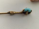 a gold and turquoise bead on a stick on a table