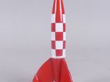 a small red and white rocket toy on a white surface