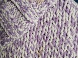 a close up of a woman ' s hand holding a purple and white knitted bag