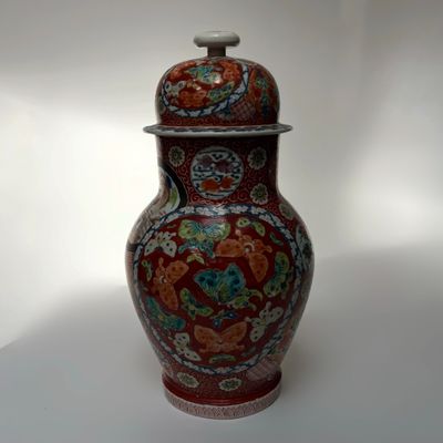 a red vase with a lid sitting on a table