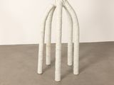 an image of a white table with three legs on a cement floor