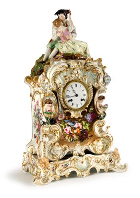 a clock with a figurine of a woman sitting on top of it