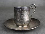une tasse et une soucoupe en argent posées sur une soucoupe