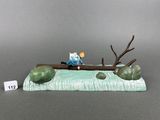 a figurine of a man sitting on a tree branch
