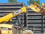 une grosse machine jaune garée devant un tas de palettes