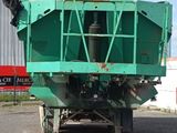 a green dump truck parked in front of a building