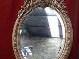 a mirror sitting on a wooden stand in front of a red curtain
