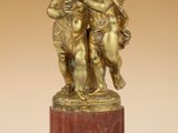 une figurine antique en bronze représentant deux chérubins, posée sur un socle en marbre