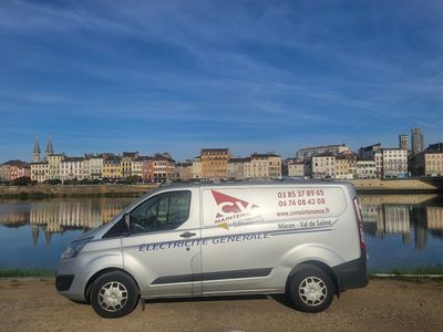 une camionnette garée au bord d'un plan d'eau, avec une ville en arrière-plan